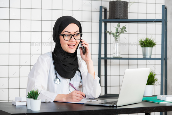 portrait of beautiful muslim female doctor using mobile phone - Stock Photo - Images