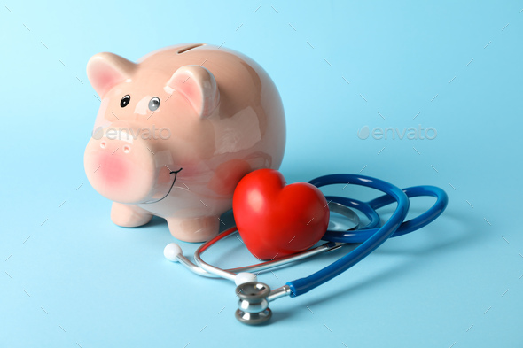 Stethoscope and piggy bank on blue background, space for text - Stock Photo - Images