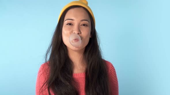 Asian woman blowing bubble gum.