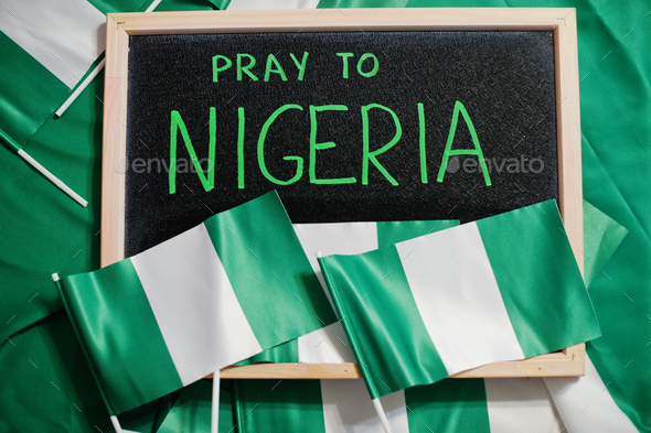 Pray to Nigeria. Text on board with nigerian flags. - Stock Photo - Images