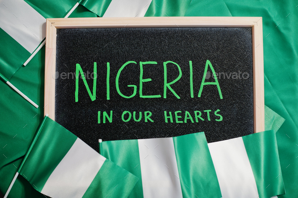 Nigeria in our hearts. Text on board with nigerian flags. - Stock Photo - Images