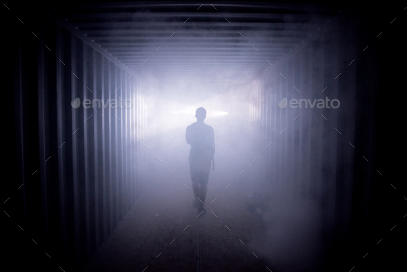 Silhouette of a man walking in a dark tunnel to the light, concept of death