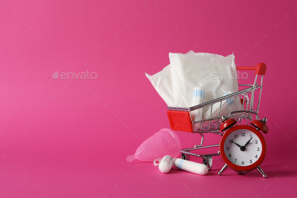 Shop trolley with menstruation period accessories on pink background, space for text