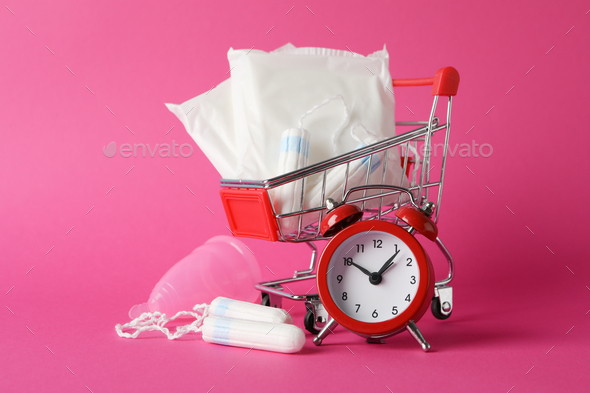 Shop trolley with menstruation period accessories on pink background, close up
