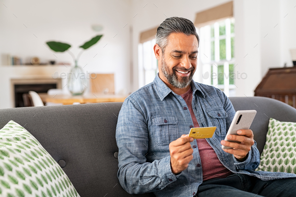 Mixed race man paying online on mobile phone - Stock Photo - Images