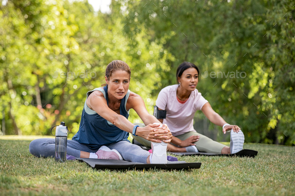 Two women doing stretching exercise at park - Stock Photo - Images