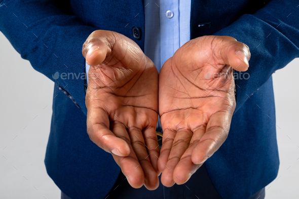 Close up of african american businessman with cupped hands against grey  background Stock Photo by Wavebreakmedia