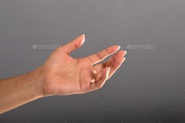 Close up of hand holding an invisible object against grey background - Stock Photo - Images