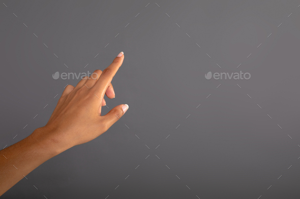 Close up of hand touching invisible screen against grey background - Stock Photo - Images