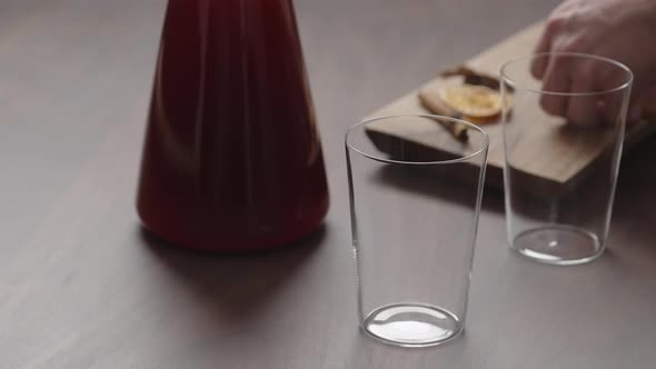 Slow Motion Man Hand Serving Mulled Wine in Thin Tumbler Glasses on Walnut Table alt