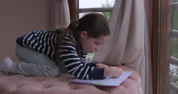 A Little Girl Drawing with Pencils at Home