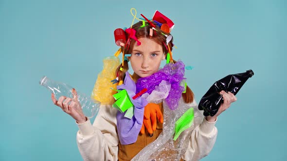 Girl with plastic garbage on herself holding two plastic bottles.