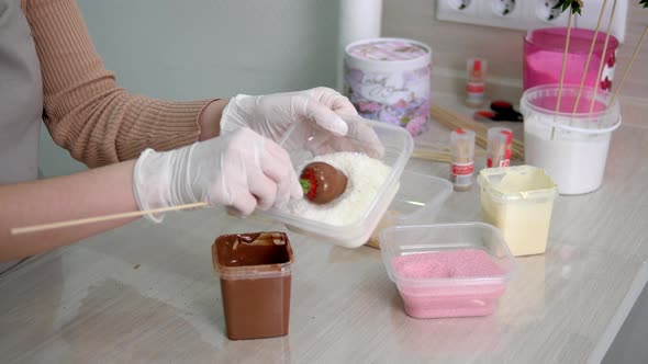 A Girl in White Gloves Prepares Strawberries in Chocolate and Coconut Shavings