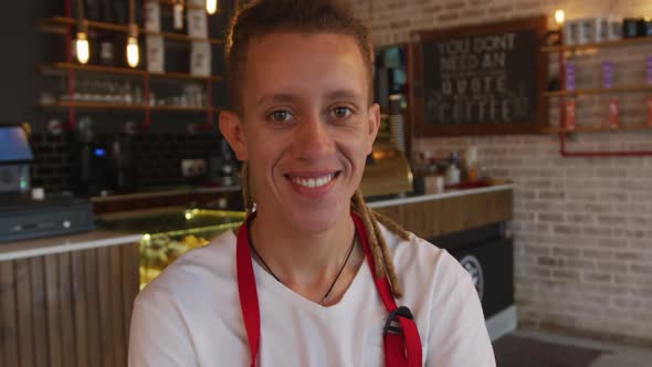 Portrait of mixed race barista with dreadlocks looking at the camera and smiling alt