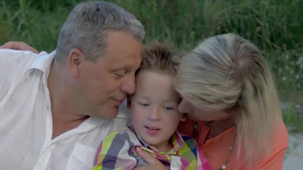 Grandparents Hugging and Kissing Their Grandson alt