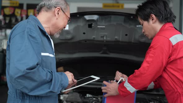 Two male mechanic checking and repair the engine at car garage service, automobile technician alt