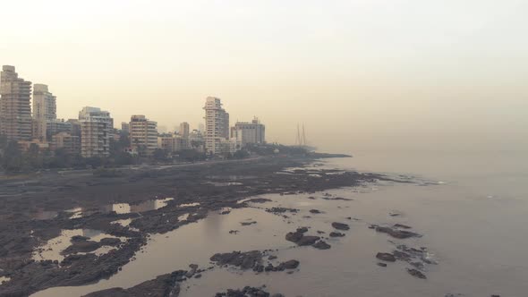 Drone shot of the rocky Mumbai coast at sunrise with the sealink in the background alt
