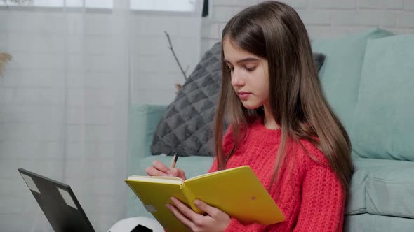 Beautiful Girl Making Notes of Online Lecture Lesson Sitting on the Floor Carpet alt