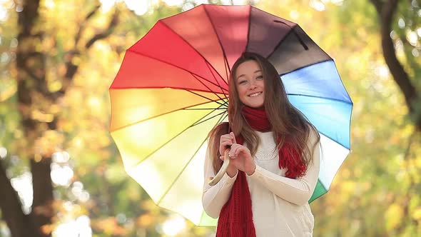 Teen girl in red scarf with umbrella at autumn outdoor