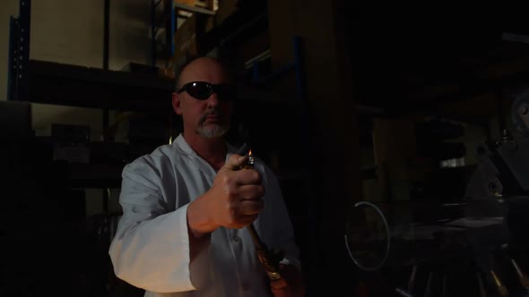 Front view of mature male worker lighting glass blowing torch in glass factory 4k alt