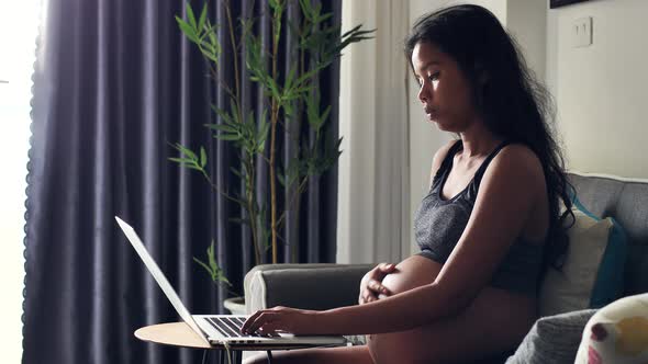 Young Pregnant Woman Working at Home Touching Her Belly and Talking to the Baby alt