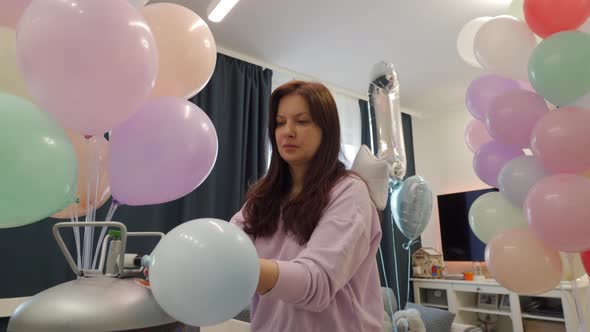 Woman Using Helium Tank Blowing Up Balloons to Decorate Home for Party Colorful Balloons for alt