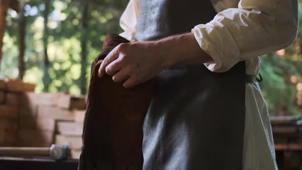Smithy Worker Puts on Fireproof Gloves Before Working with Redhot Metal alt