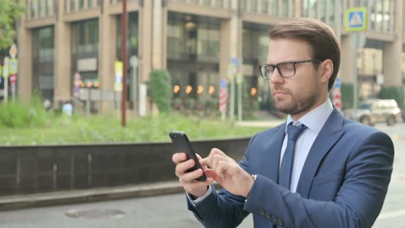 Businessman using Smartphone while Walking in Street alt