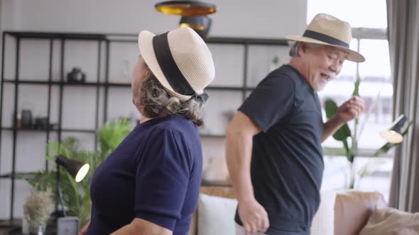 Slow motion Asian mature senior couple is dancing and smiling at home.