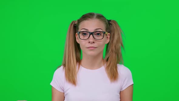 Young Female with Glasses Standing in Green Room and Looks at the Camera the Woman Expresses alt
