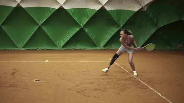 Backside View of Energetic Young Woman with a Prosthesis Down Her Knee is Focused on Beating the alt