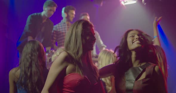 Female friends taking self photograph with mobile phone while enjoying music in nightclub