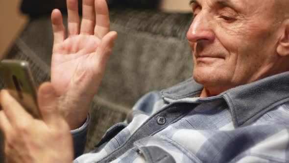 A pensioner communicates using a smartphone in a video chat. alt