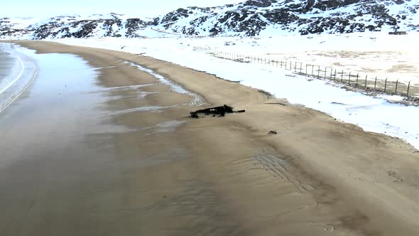 Aerial Top View of Old Wrecked Fishing Ships Drowned at the Sea Shore in Snowy Winter Season alt