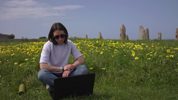 The Girl Works at the Laptop Sitting on the Green Grass alt