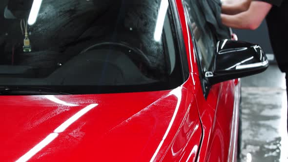 Car Washing Service  a Man Washing a Red Car with a Rag alt