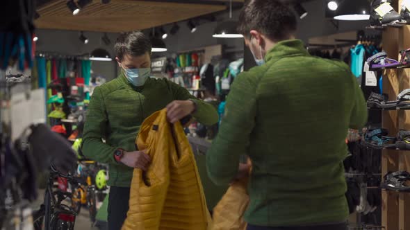 Man in Protective Mask Shopping Outdoor Equipment in Sports Store During Quarantine Covid 19 alt