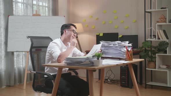 Asian Man Thinking And Looking At Paper Then Raising Index Finger While Working With Documents alt
