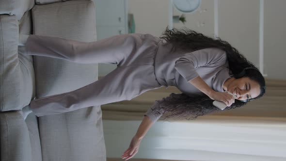 Vertical View of Attractive Young Funny Woman Girl Wear Headphones Dancing on Cozy Sofa at Home alt