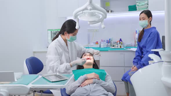 Asian female dentist adjust dental surgical light then start checking or examining tooth for patient alt