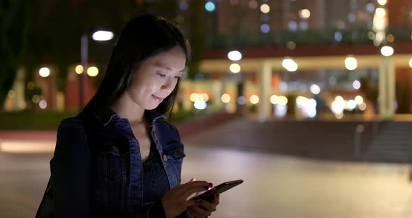 Woman use of mobile phone on earphone at night alt