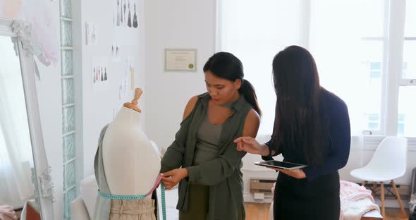 Fashion designers using tablet while measuring dress makers model  alt