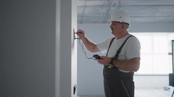 A Male Electrician Checks the Voltage in the Network with a Wire Tester Preparing to Install a Smart alt