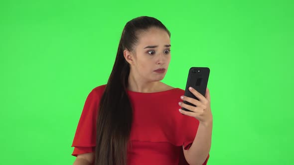 Portrait of Pretty Young Woman Is Angrily Talking for Video Chat Using Mobile Phone. Green Screen alt