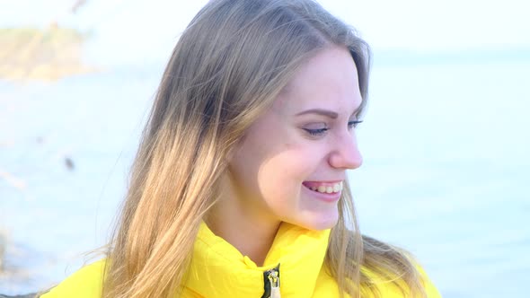 A Young Happy Smiling Shy Blueeyed Woman in Nature in a Yellow Jacket on a Spring Autumn Sunny Day
