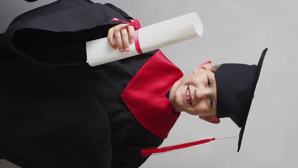 Portrait of Confident Student in Graduation Gown Showing a Diploma in His Hand alt