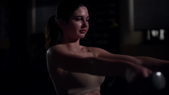 Confident Slim Woman Training Hands with Dumbbells in Slow Motion in Darkness alt