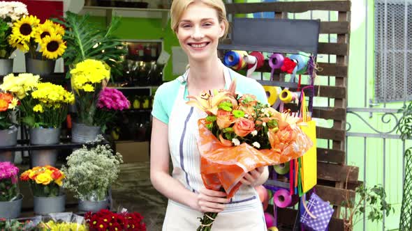 Female florist holding a bouquet of flowers in flower shop alt