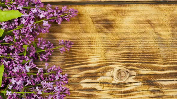 Bouquet of Lilac Flowers Lie on an Old Burnt Wooden Background alt