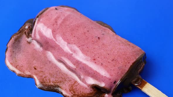 The chocolate ice cream sundae lies on a blue background and melts slowly. 4K video food close-up. alt